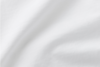 A close-up of smooth, white fabric with soft folds and subtle shadows, creating a gentle texture across the surface.
