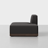 A modern, dark gray armless sofa with a low wooden base, viewed from the side against a plain white background.