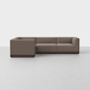 A modern brown L-shaped sectional sofa with low backs and square armrests, set on a wooden base, positioned on a light gray floor against a plain white background.