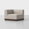 A modern, light beige upholstered corner chair with a boxy design and a dark wooden base, set against a plain white background.