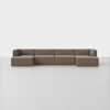 A modern, modular brown sectional sofa with wooden base, arranged in an L-shape against a plain white background on a smooth, light-colored floor.