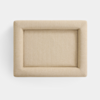A rectangular, beige upholstered ottoman viewed from above, with a soft cushion and rounded edges, set against a plain white background.
