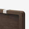 Close-up of the top corner of a wooden headboard with rounded edges, featuring a light-colored fabric strap wrapped around the edge against a plain white background.