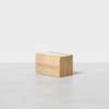 A light wood two-drawer rectangular nightstand with clean, minimalist lines sits on a smooth, light gray floor against a plain white background.