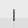 A dark wooden vertical bookshelf with five evenly spaced shelves stands alone on a light, empty floor against a plain white background.
