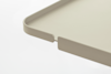 A close-up view of the corner of a beige tray with raised edges and a small, rectangular notch cut out along the rim. The background is white.