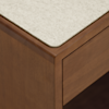 A close-up of the corner of a wooden table or desk with a light-colored, textured tabletop and a smooth, polished wooden edge and side panel.