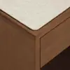 A close-up of the corner of a wooden table or desk with a light-colored, textured tabletop and a smooth, polished wooden edge and side panel.