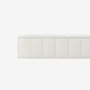 Side view of a white, rectangular mattress with a quilted, textured fabric cover and stitched vertical panels, isolated on a white background.