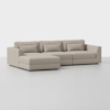 A modern, light beige sectional sofa with clean lines, low backrests, and matching rectangular cushions, positioned on a plain white background.