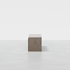 A wooden desk with a minimalist design viewed from the side, set against a plain white background on a light, smooth floor.