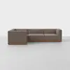 A modern L-shaped sectional sofa with brown upholstery and a wooden base, placed on a light gray floor against a plain white background.