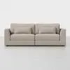A modern, light beige upholstered sofa with square arms, two seat cushions, two back cushions, and two matching rectangular throw pillows, set against a plain white background.