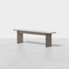 A simple wooden bench with a rectangular seat and two wide, flat legs, finished in a light grayish-brown color, set against a plain white background.