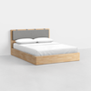 A modern wooden bed frame with a light wood finish, featuring a simple headboard with a cushioned gray panel and neatly made white bedding, set against a plain white background.