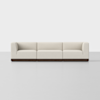 A modern, light beige, three-seat sofa with low square arms and a dark wooden base, set against a plain white background.