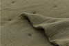 A close-up of a textured, olive-green fabric blanket with a grid pattern. Part of the blanket is folded over, revealing its soft, quilted surface and subtle stitched detailing.