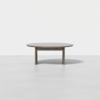 A round, light gray wooden table with three legs, set against a plain white background.