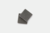 Two square, dark gray washcloths are stacked slightly askew on a plain white background.