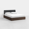 A modern bed with a dark wooden frame, white bedding, two pillows, and a black upholstered headboard, set against a plain white wall and floor.