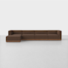 A modern sectional sofa with brown upholstery and a wooden base, featuring a left-facing chaise lounge, placed in a minimal, white room.