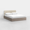 A modern bed with a light beige upholstered headboard, white bedding, two pillows, and a light wood platform frame, set against a plain white background.