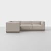 A modern L-shaped sectional sofa with light beige upholstery and a low wooden base, set against a plain white background.