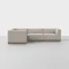 A modern L-shaped sectional sofa with light beige upholstery and a low wooden base, set against a plain white background.