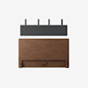 A minimalist image showing a wooden headboard below a dark gray, wall-mounted cushion pad with four black metal brackets, all against a plain white background.