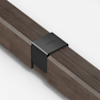 A close-up of two wooden beams joined by a matte black metal bracket engraved with the word THUMA on a white background.