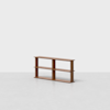 A minimalist wooden bookshelf with three shelves and two vertical dividers stands on a light gray floor against a plain white background.