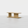 A minimalist rectangular wooden coffee table with an open shelf below, featuring clean lines and a light wood finish, set against a plain white background.