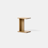 A minimalist, light wood side table with a modern, C-shaped design, set against a plain white background.