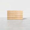 A minimalist light wood dresser with eight drawers is placed on a smooth, light gray floor against a plain white background.