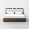 A modern wooden bed frame with a beige upholstered headboard, made up with white sheets, two pillows, and a white blanket, set against a plain white wall and light gray floor.