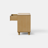 A minimalist wooden cabinet with a light finish, rectangular shape, and short cylindrical legs, placed on a light gray floor against a plain white background.