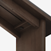 Close-up view of the underside of a dark wooden table, showing a joint where the leg meets the tabletop with visible screws and smooth, polished surfaces.