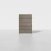 A minimalist wooden dresser with five horizontal drawers stands on a light gray floor against a plain white background.