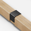 A close-up of two light wood beams joined together by a sleek, black metal bracket engraved with the word THUMA on a white background.