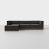 A modern, dark gray L-shaped sectional sofa with low backrests and a wooden base, placed on a light gray floor against a plain white background.