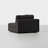 A modern, dark gray upholstered corner sofa chair with clean lines and a low back, set against a plain white background.