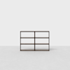A dark wooden, minimalist bookshelf with six open rectangular shelves, standing on a light gray floor against a plain white background.