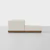 A modern, light beige sectional sofa with a wooden base is shown from the side against a plain white background. The set includes a low-profile seat and an adjacent ottoman.