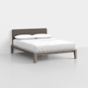 A modern bed with a wooden frame, light brown legs, a dark upholstered headboard, and white bedding with two pillows, set against a plain white wall and floor.
