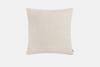 A rectangular beige pillow with a plain, textured fabric cover, shown against a white background. There is a small black fabric tag on the lower right edge.