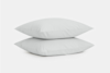 Two plain white pillows are stacked neatly on top of each other against a light gray background.