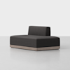 A modern, minimalist black armless sofa with a low wooden base and a single backrest, placed on a plain light-colored floor against a white background.