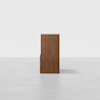 A tall wooden cabinet with a smooth finish, viewed from the side against a plain white background. The cabinet has a simple, modern design with clean lines.