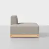 A modern armless sofa with light gray upholstery and a rectangular shape, featuring a low wooden base, shown from the side against a plain white background.