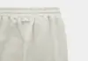 Close-up of the waistband and upper section of light grey sweatpants, showing an elastic waistband with gathered fabric and a simple, minimal design.